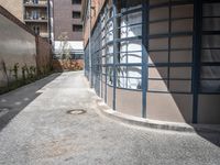 an empty sidewalk and brick building with glass front doors on it is next to a path