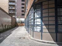 an empty sidewalk and brick building with glass front doors on it is next to a path