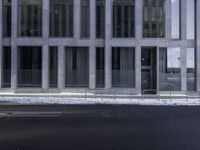 an empty street in front of a large office building, while a man takes his picture on his cell phone