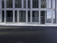 an empty street in front of a large office building, while a man takes his picture on his cell phone