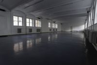 a room filled with windows and floors in an empty building with a dark gray floor