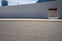 the side of a building next to a street curb with an empty parking lot in the background