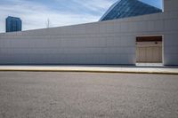 the side of a building next to a street curb with an empty parking lot in the background