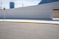 the side of a building next to a street curb with an empty parking lot in the background
