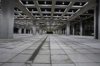 an empty concrete floor and ceiling area in a city building at night with lights on it