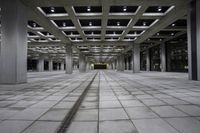 an empty concrete floor and ceiling area in a city building at night with lights on it