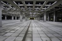 an empty concrete floor and ceiling area in a city building at night with lights on it