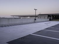 a person walking through an empty parking lot on a cloudy day at sunset in the city