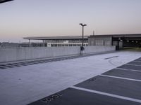 a person walking through an empty parking lot on a cloudy day at sunset in the city