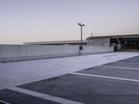 a person walking through an empty parking lot on a cloudy day at sunset in the city