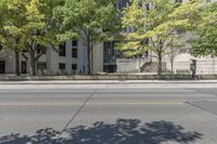 this is a parking meter in front of the city building on a street corner with trees, benches and parking meters