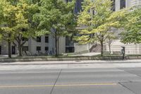 this is a parking meter in front of the city building on a street corner with trees, benches and parking meters