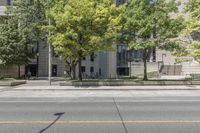 this is a parking meter in front of the city building on a street corner with trees, benches and parking meters