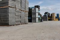 a pile of pallets and some buildings are in the distance in an empty lot