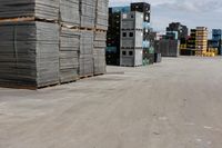 a pile of pallets and some buildings are in the distance in an empty lot