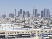 a city skyline with skyscrapers behind it and cars parked below the buildings on the lot