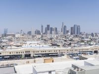 a city skyline with skyscrapers behind it and cars parked below the buildings on the lot