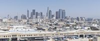 a city skyline with skyscrapers behind it and cars parked below the buildings on the lot