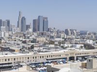 a city skyline with skyscrapers behind it and cars parked below the buildings on the lot