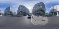 a fish eye view of the city buildings of a large intersection with a car on the street