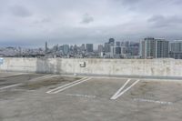 two parking spaces on a concrete roof with a view of city buildings in the background