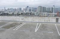 two parking spaces on a concrete roof with a view of city buildings in the background