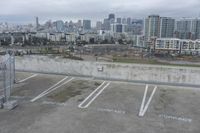 two parking spaces on a concrete roof with a view of city buildings in the background