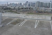 two parking spaces on a concrete roof with a view of city buildings in the background