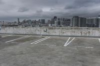 two parking spaces on a concrete roof with a view of city buildings in the background