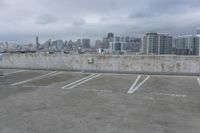 two parking spaces on a concrete roof with a view of city buildings in the background