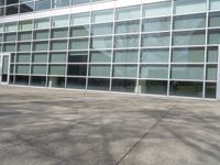 there is an empty concrete parking lot next to the building with glass windows and trees on it