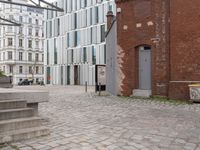 an empty brick sidewalk in the center of a city area and buildings with a metal door