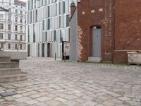 an empty brick sidewalk in the center of a city area and buildings with a metal door