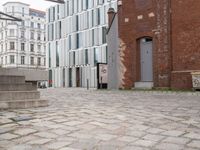 an empty brick sidewalk in the center of a city area and buildings with a metal door