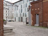 an empty brick sidewalk in the center of a city area and buildings with a metal door