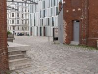 an empty brick sidewalk in the center of a city area and buildings with a metal door