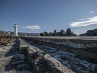 the lighthouse is surrounded by huge rocks on a clear day, near a large city