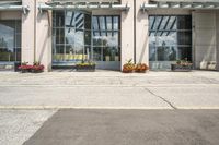 people cross the street in front of an entrance to the city court building, with potted flower plants lining either side of the entry way