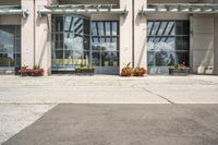 people cross the street in front of an entrance to the city court building, with potted flower plants lining either side of the entry way