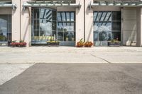 people cross the street in front of an entrance to the city court building, with potted flower plants lining either side of the entry way