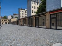 the sidewalk is paved with stones and has a bench in front of it, with no people inside