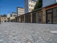 the sidewalk is paved with stones and has a bench in front of it, with no people inside