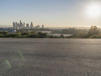 the person riding his bike through the parking lot near a city skyline as he goes off into the distance