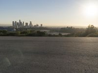 the person riding his bike through the parking lot near a city skyline as he goes off into the distance