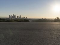 the person riding his bike through the parking lot near a city skyline as he goes off into the distance