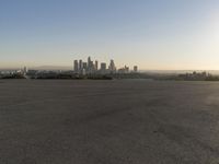 the person riding his bike through the parking lot near a city skyline as he goes off into the distance