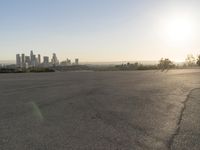 the person riding his bike through the parking lot near a city skyline as he goes off into the distance