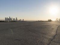 the person riding his bike through the parking lot near a city skyline as he goes off into the distance