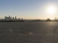 the person riding his bike through the parking lot near a city skyline as he goes off into the distance