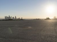 the person riding his bike through the parking lot near a city skyline as he goes off into the distance